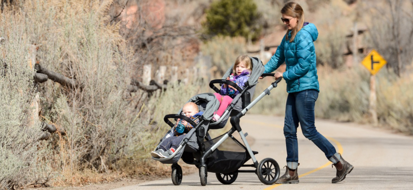 Mamica z otokoma v tandemskem vozičku za dvojčke Mamica z otokoma v tandemskem vozičku za dvojčke